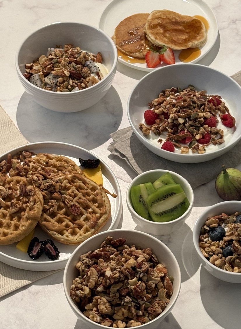 Breakfast spread with granola bowls, waffles, pancakes, and fresh fruit