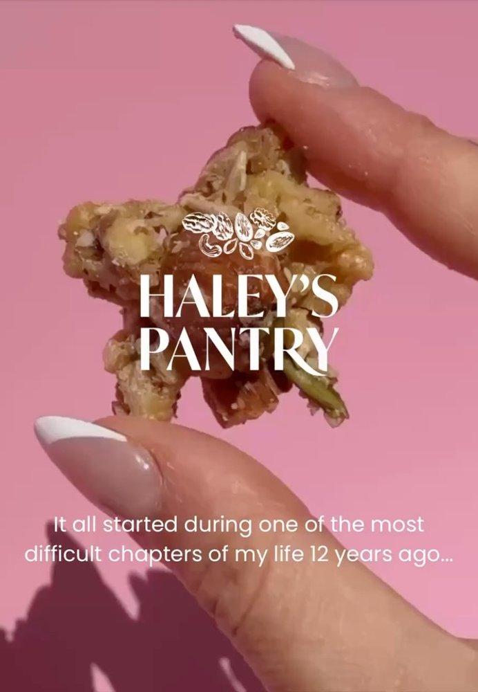 Hand holding a granola cluster with the Haley's Pantry logo